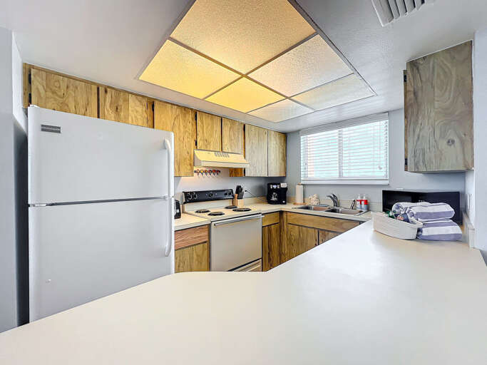 Prepare meals with ease in this well-lit kitchen featuring modern appliances, ample counter space, and a charming coastal vibe.