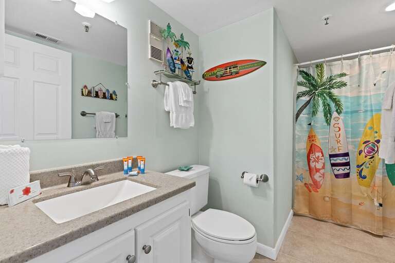 Bright bathroom featuring a surf-inspired shower curtain, modern amenities, and coastal decor.