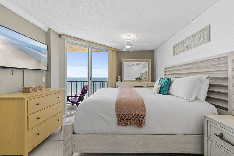Luxurious bedroom with a private balcony, breathtaking ocean views, and modern decor.
