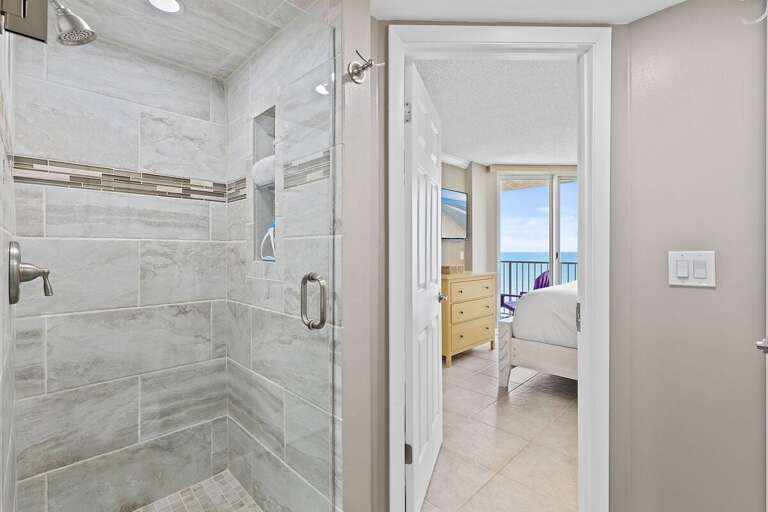 Refresh in a beautifully tiled walk-in shower with elegant fixtures and natural lighting.