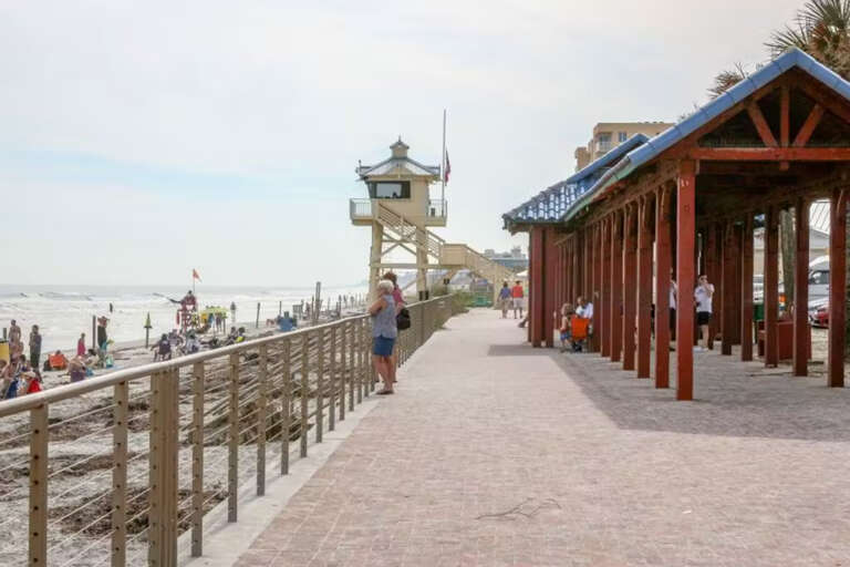 Relax along the scenic boardwalk, with beach views, shaded seating, and a lifeguard tower keeping watch over the waves.