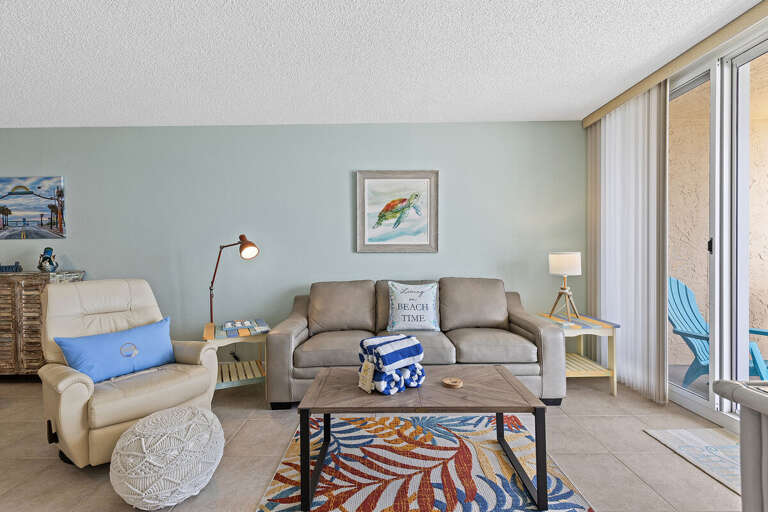 Relax in a stylish living room with a beach vibe, comfy furniture, and balcony access.
