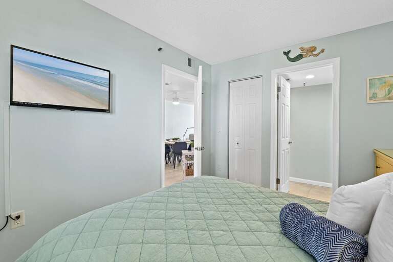 Rest comfortably in a vibrant guest bedroom with pastel tones, plush bedding, and a wall-mounted TV.