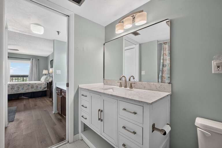 Freshen up in this bright ensuite bathroom featuring a spacious vanity, large mirror, and convenient