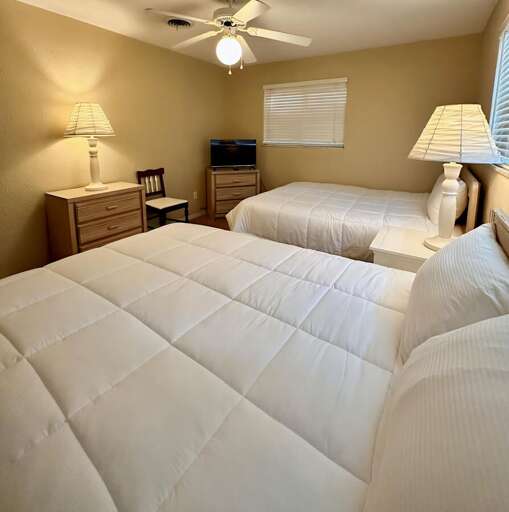Comfortable and spacious bedroom featuring two full-size beds with cozy white bedding, soft carpet,