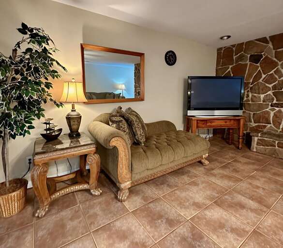 Cozy corner with a plush chaise lounge, decorative side table, and flat-screen TV.