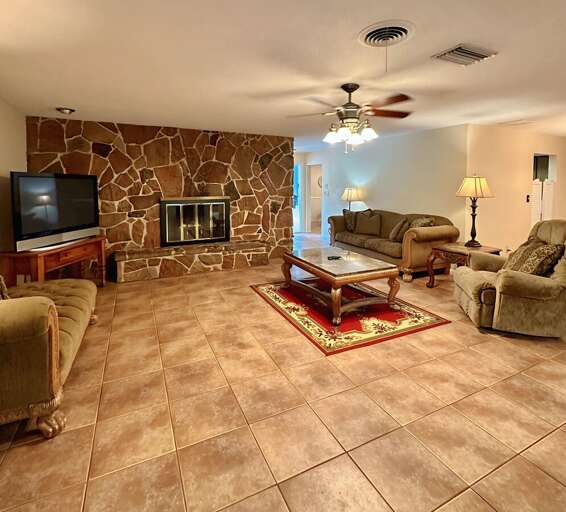 Spacious living room comfy sofas, recliner, flat-screen TV, and tile floors — perfect for relaxing after a day out!