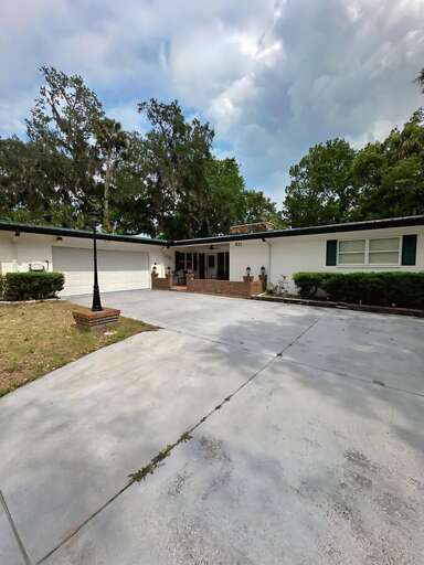 Spacious mid-century style home with a clean, wide driveway, two-car garage, and charming brick-accented front porch. Nestled under beautiful moss-draped oak trees.