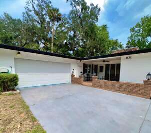 Welcoming front exterior with a spacious driveway, two-car garage, and a cozy covered patio — perfect for enjoying your morning coffee or evening chats under the ceiling fan.