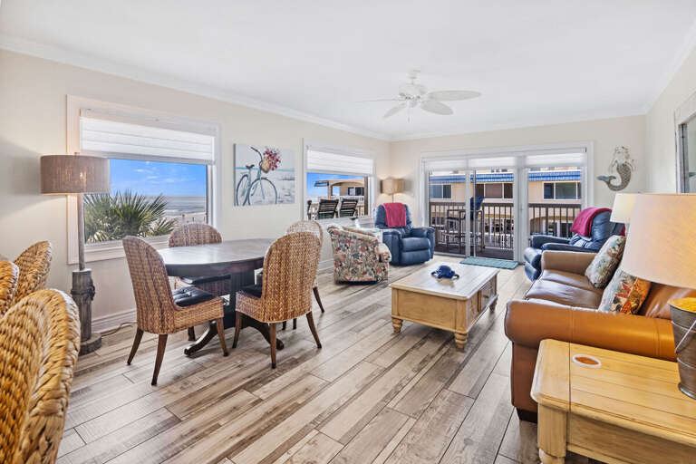 Relax in this inviting beach condo living space featuring plush seating, coastal décor, and stunning ocean views from large windows—perfect for unwinding after a day in the sun and surf.
