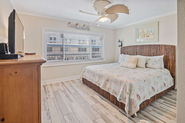 Unwind after your beach adventures in this spacious king bedroom, featuring a woven headboard, seashell bedding, and coastal décor for a relaxing seaside retreat.