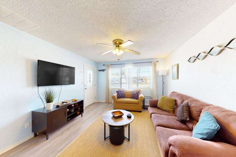 Brightly Lit Living Room With Plush Seating And Television, Featuring A Wooden Floor