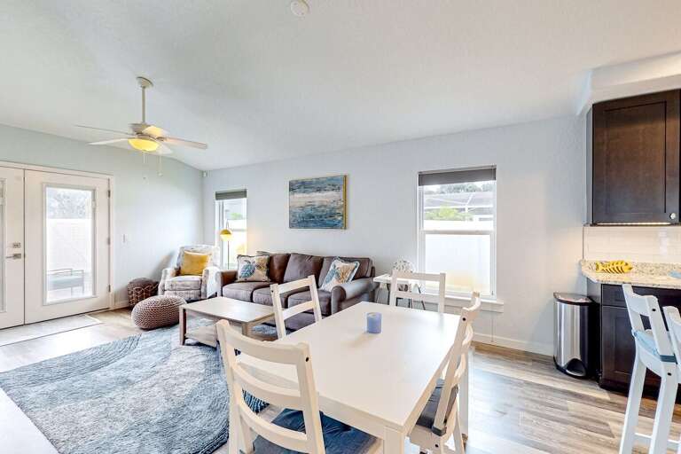 Bright, beach-style living and dining area with cozy seating, natural light, and easy access to the kitchen—perfect for unwinding after sunny days by the shore.