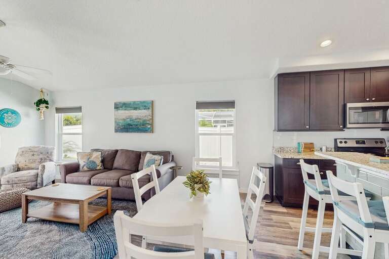 Charming beach-inspired living and dining area with comfy seating, bright windows, and easy access to the kitchen—an inviting spot to relax after fun-filled coastal adventures.
