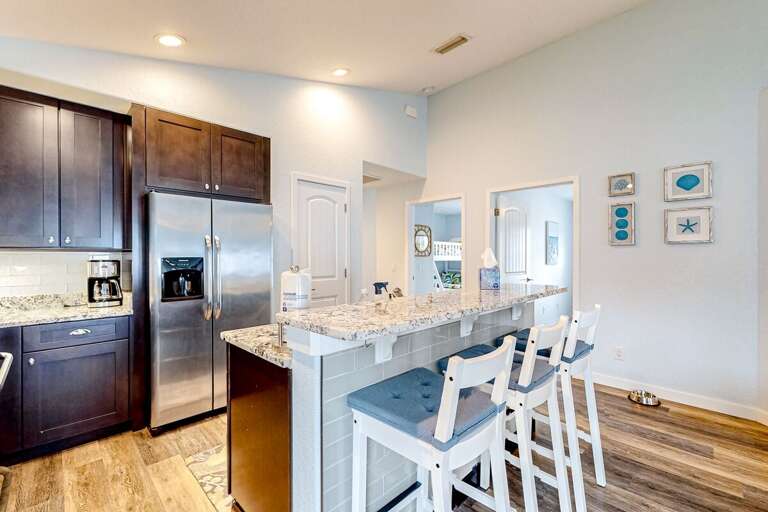 Inviting beach-style breakfast bar with granite counters and comfy seating, offering a perfect spot for quick bites before heading out to enjoy sun, sand, and coastal fun.