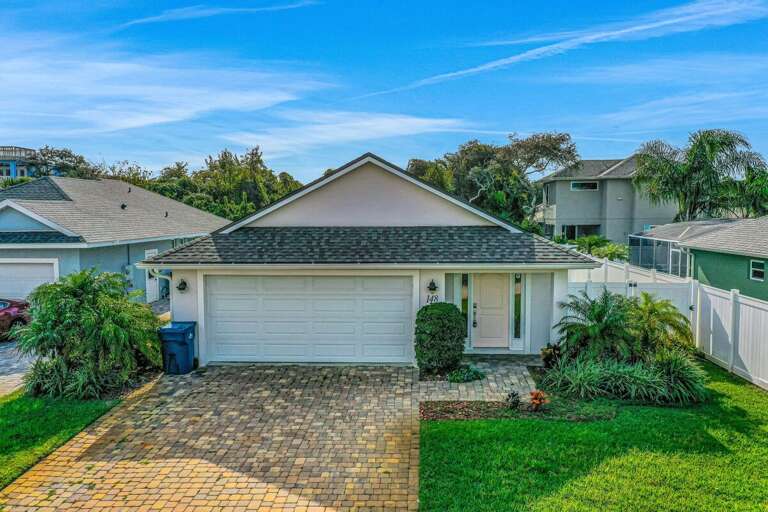 Inviting beach-style home with lush landscaping, a spacious driveway, and a bright entry—your perfect starting point for a relaxing coastal getaway.