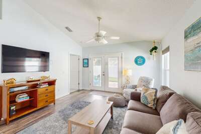 Relax in this airy beach-style living room featuring cozy seating, coastal décor, and easy access to the patio. A perfect spot to unwind after a sun-soaked beach day.