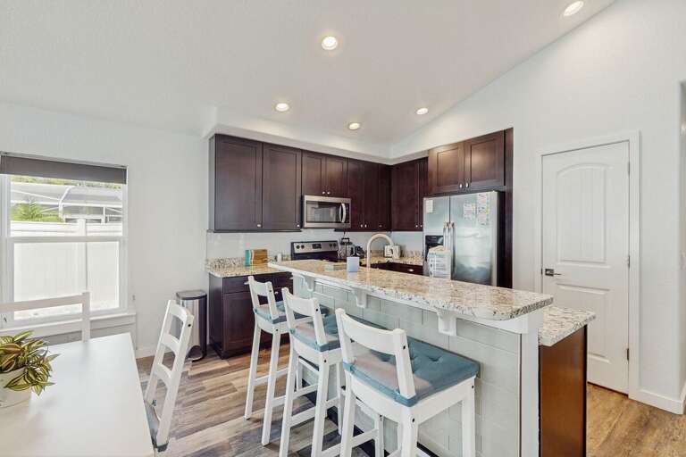 Spacious beach-style kitchen featuring granite counters, stainless appliances, and a cozy breakfast bar—perfect for enjoying meals before heading out for sun and surf.