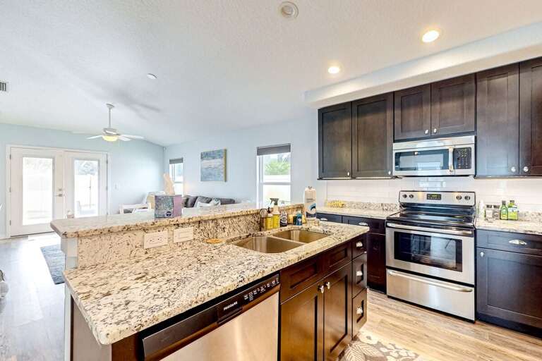 Spacious beach-style kitchen with granite counters, stainless appliances, and an open view to the airy living area—perfect for relaxed coastal living and entertaining after a day by the shore.