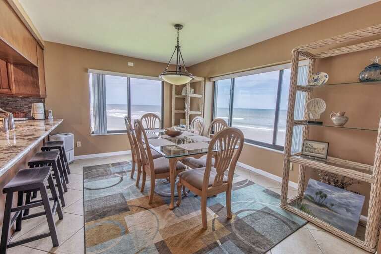 Dine with a view in this bright beachfront dining area featuring panoramic ocean vistas, natural light, and coastal décor—perfect for enjoying meals and sunsets during your beach stay.