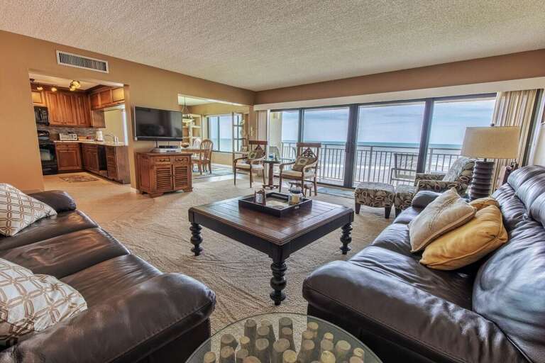 Enjoy this inviting oceanfront living area with panoramic beach views, cozy leather seating, and an