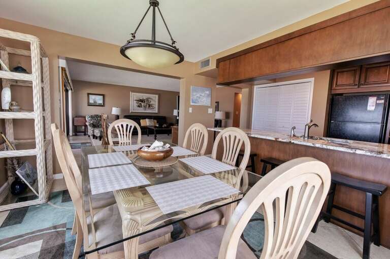Gather for meals in this inviting beachfront dining area with a glass-top table, open kitchen, and coastal décor—perfect for sharing oceanview meals and relaxing during your beach stay.