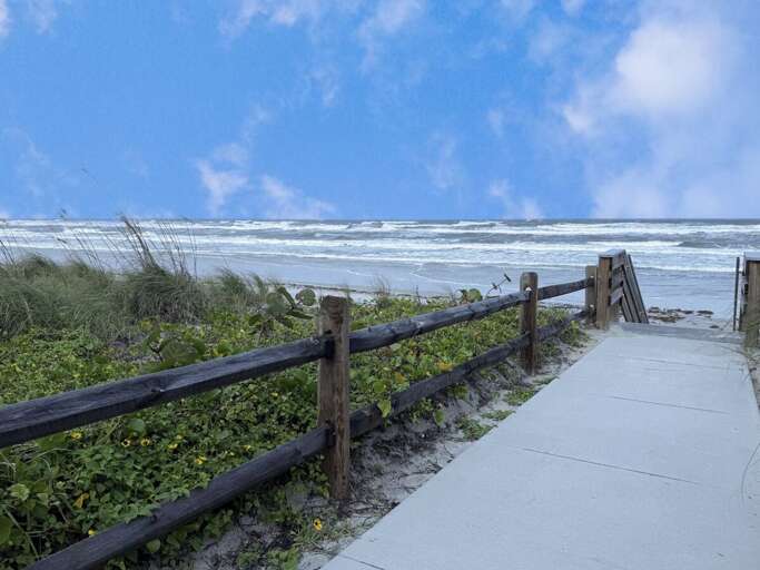 Boardwalk path opening to expansive sandy shores and rolling waves. This prime beach stay location offers effortless access to sun, surf, and breathtaking ocean views for a true seaside escape.