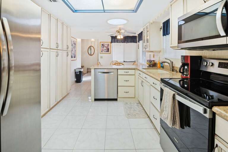 Bright, spacious kitchen with stainless steel appliances, ample cabinetry, and a breakfast