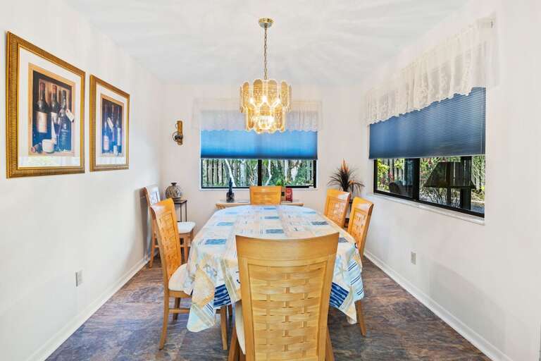 Inviting dining space with elegant lighting and garden-view windows—perfect for shared meals during your beach stay. Enjoy relaxed gatherings and coastal charm just minutes from the sand and sea.