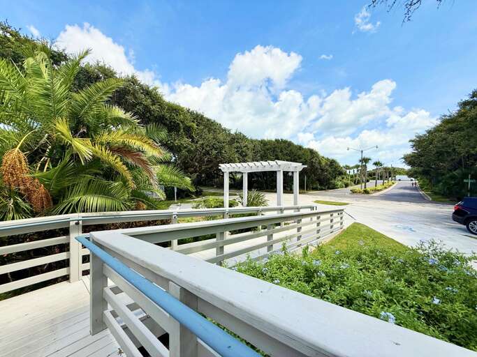 Welcoming boardwalk-style entrance surrounded by tropical palms and coastal greenery. This inviting
