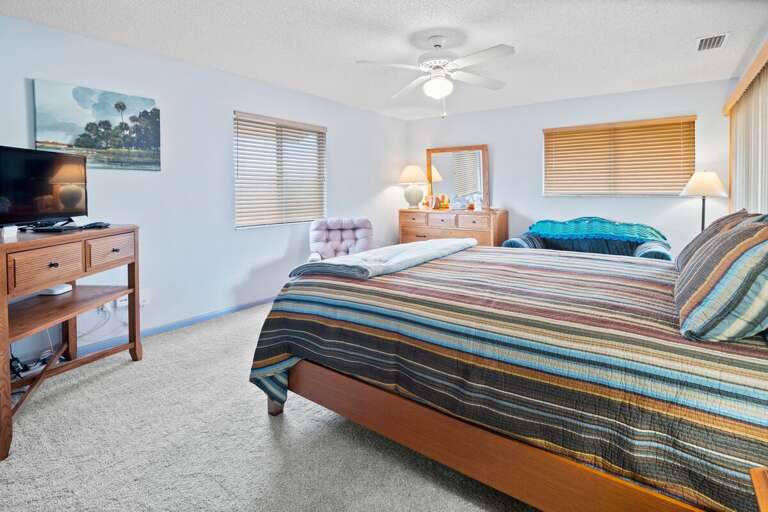 Retreat to this comfortable beach stay primary bedroom featuring a plush bed, TV, and cozy seating