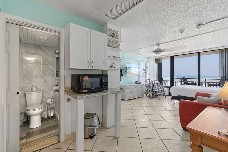 This bright beach stay features an open layout with kitchen, dining, and sleeping areas, plus easy access to a private balcony with ocean views—perfect for a relaxing and convenient coastal getaway.