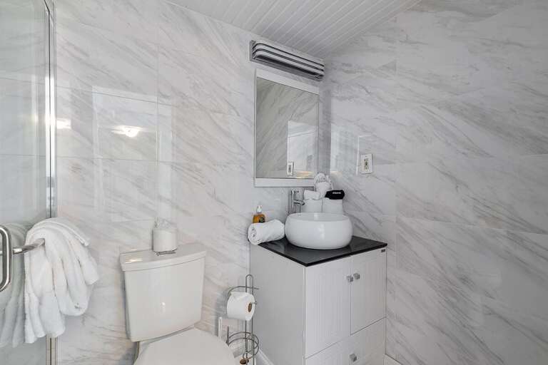 This modern bathroom features a sleek vanity, vessel sink, and elegant tile design. Fresh towels and clean finishes provide a comfortable, spa-like experience during your beach stay getaway.