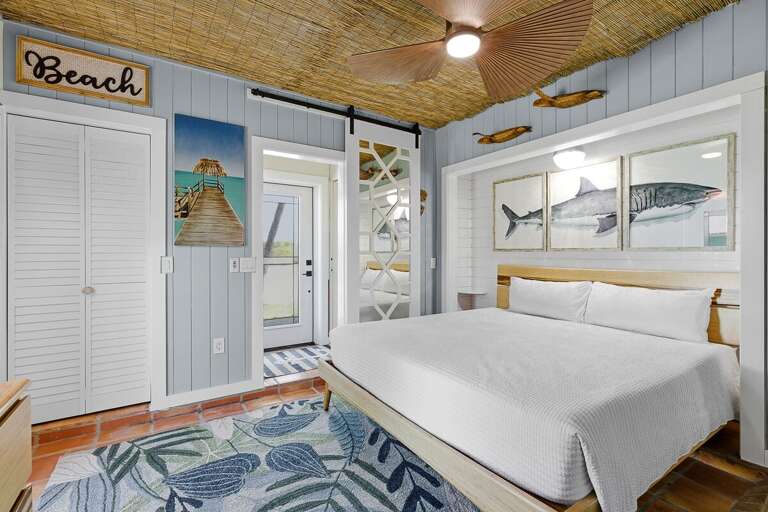Bright king bedroom with coastal décor, tropical ceiling, and beachy accents. Enjoy a relaxing beach stay with comfortable furnishings and easy access to outdoor spaces for a true seaside escape.