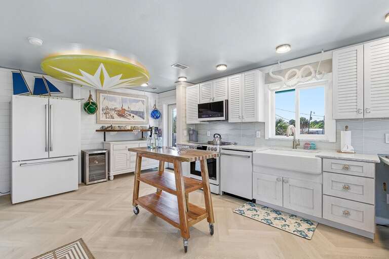 Charming coastal kitchen with modern appliances, farmhouse sink, and island workspace. Perfect for a