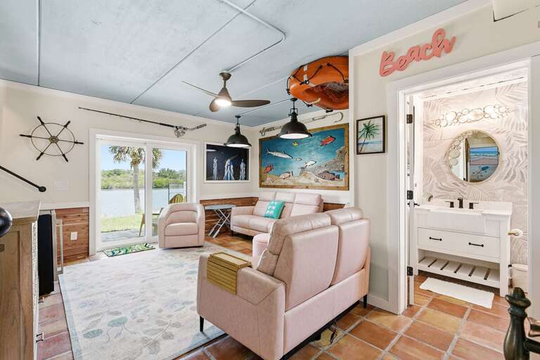 Inviting coastal living space with nautical décor, comfortable seating, and sliding doors to scenic