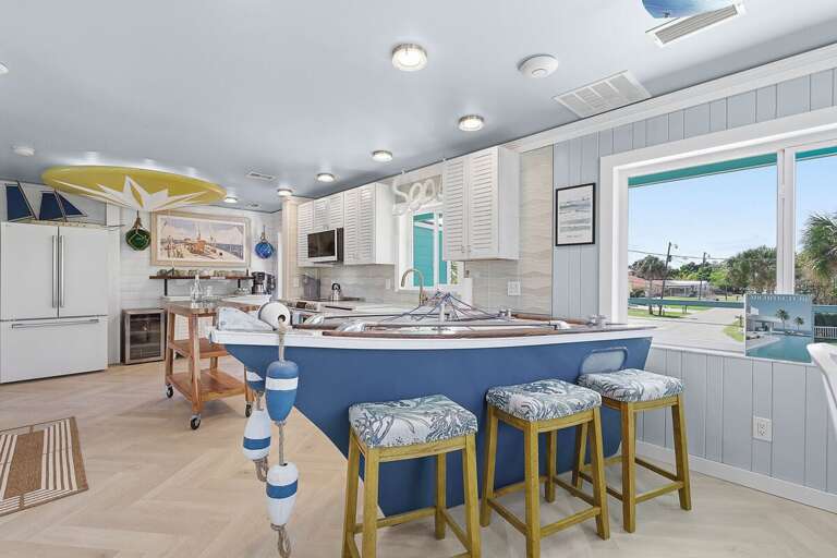 One-of-a-kind coastal kitchen featuring a boat-shaped bar, modern appliances, and bright design.