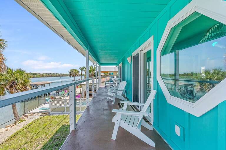 Soak in serene water views from this inviting balcony featuring Adirondack seating and breezy