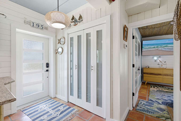 Step into your beach stay through this bright, coastal entryway featuring stylish shiplap walls, nautical accents, and easy access to living spaces. A welcoming start to your relaxing seaside getaway.