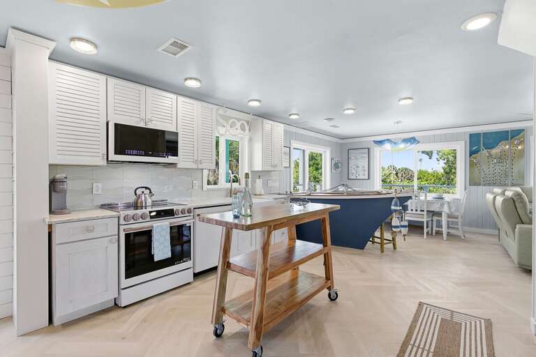 Stylish coastal kitchen featuring modern appliances, island workspace, and sunlit dining area.