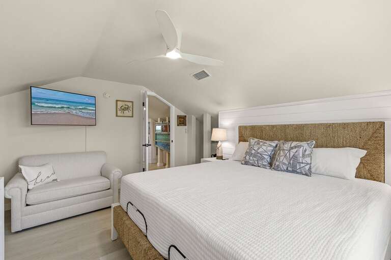 Unwind in this bright coastal bedroom featuring a plush bed, cozy seating area, and beach-inspired