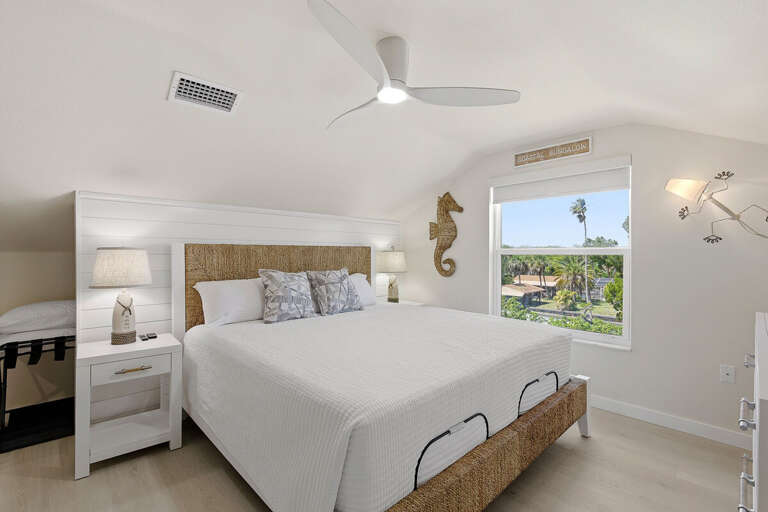 Unwind in this cozy coastal bedroom featuring a plush bed, natural textures, and sunny window views.
