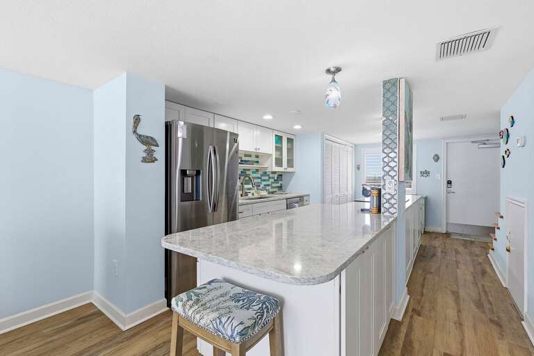 This inviting beach stay features a spacious kitchen with a large island, modern appliances, and coastal design. Perfect for cooking, gathering, and enjoying laid-back meals after a day at the beach.