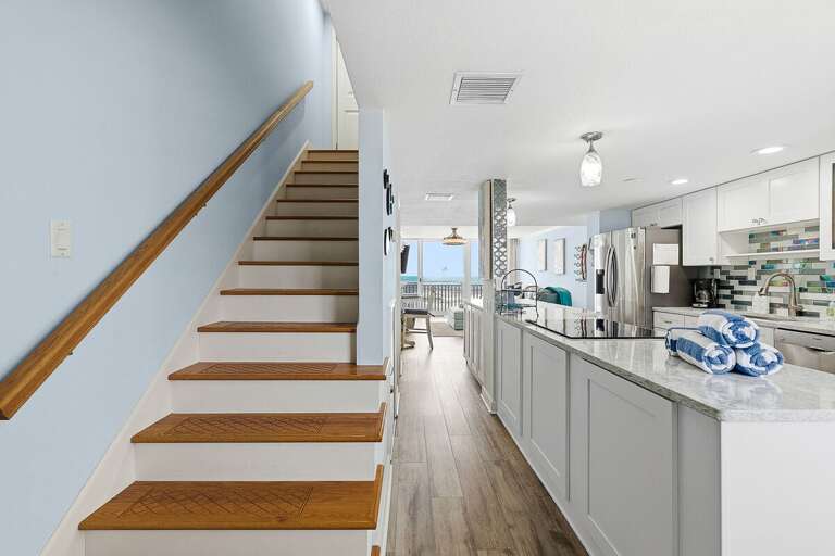 This beach stay features a bright open layout with a coastal kitchen and easy access between levels.