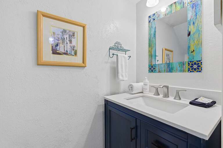 This beach stay features a charming half bath with a modern vanity, coastal accents, and colorful décor. A fresh, convenient space to refresh during your relaxing seaside getaway.