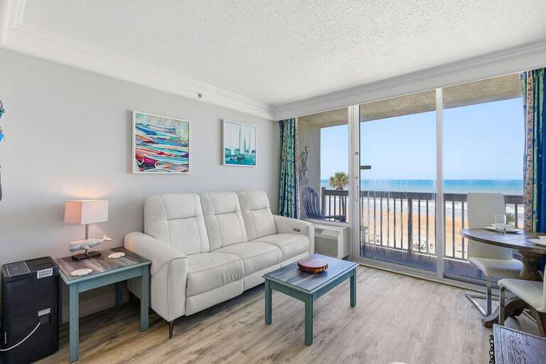 Bright beach stay living room with cozy seating and direct access to a private balcony overlooking