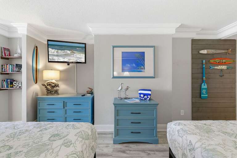 Charming beach stay bedroom featuring two beds, coastal furnishings, and a TV for added comfort. Nautical décor and relaxing tones create the perfect space to unwind after a day at the beach.