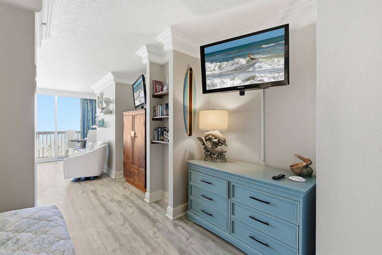 Comfortable beach stay interior featuring a TV, coastal décor, and easy access to the oceanview balcony. Relax indoors with modern comforts after a day enjoying the sun, sand, and surf.