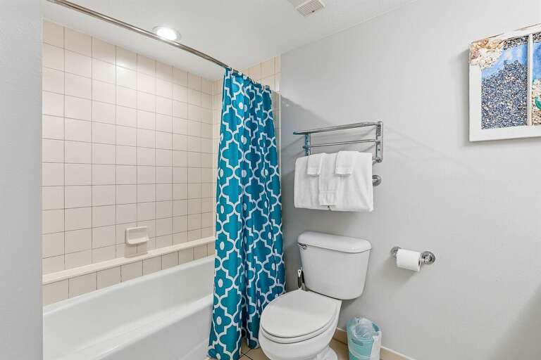 Fresh and functional beach stay bathroom featuring a full tub and shower combo, clean finishes, and plush towels. A convenient space to refresh after a day enjoying the sun, sand, and ocean.