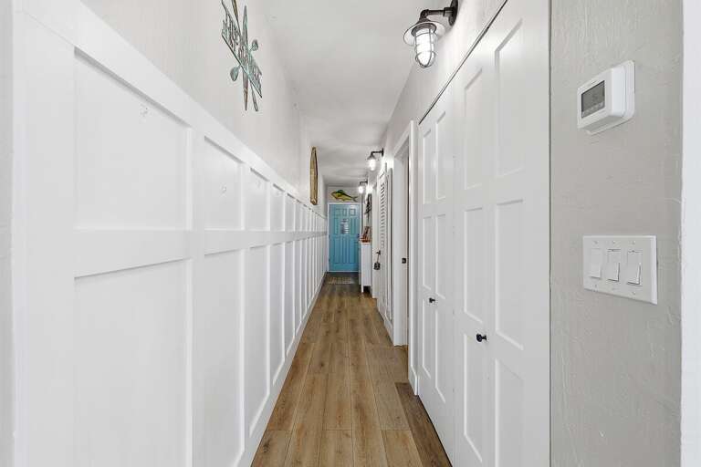 This beach stay welcomes you with a bright, coastal-inspired hallway featuring wood flooring and